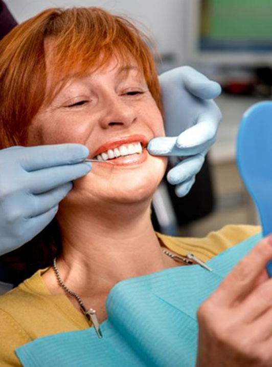 Mature dental patient holding mirror